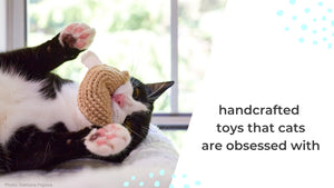 A photo of a black and white cat playing with his fortune cookie shaped crochet cat toy. The text reads, “Handcrafted toys that cats are obsessed with”